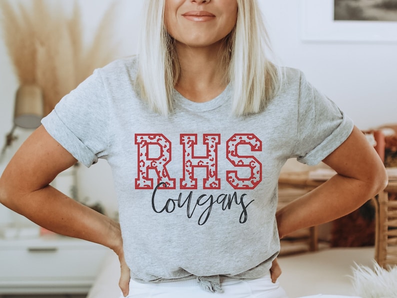 May include: A gray t-shirt with a red and white leopard print "RHS Cougars" design.