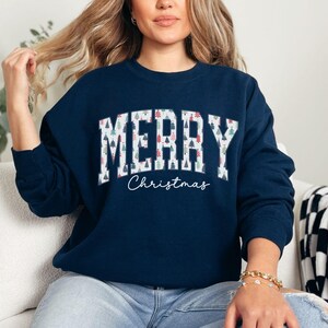 May include: A navy blue sweatshirt with a white "Merry Christmas" graphic. The text is made up of small Christmas trees.