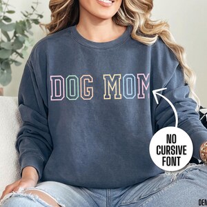 May include: A dark blue sweatshirt with the text "DOG MOM" in a rainbow colored block font.