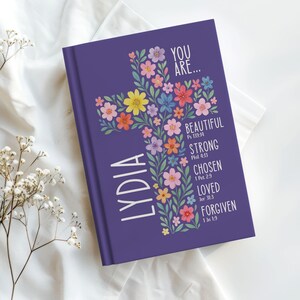 Personalized Christian journal for women and girls with a floral cross design on the cover. The front features “You Are” affirmations with Bible verses and a custom name option. Available in 8 colors, this faith-based notebook can be used for prayer journaling, Bible study notes, gratitude, reflections, and daily writing. Optional customization available for spine and back cover text. Feminine, inspirational gift idea for teens, women, church, or special occasions.