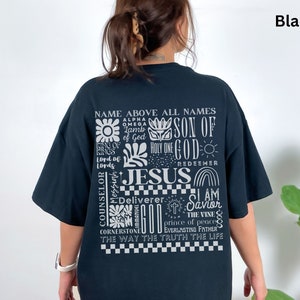 May include: Black t-shirt with a white graphic print of the words "Name Above All Names" and "Jesus" surrounded by other religious phrases and symbols.