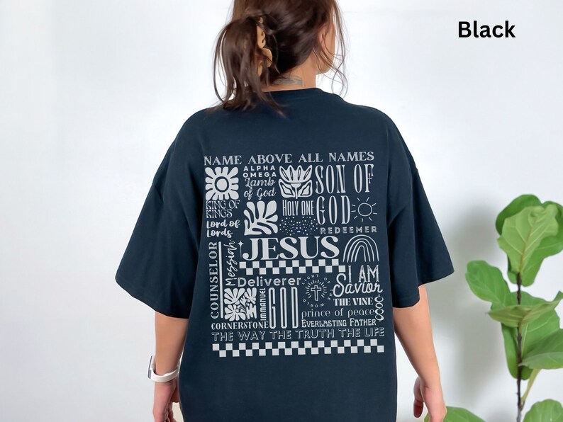 May include: Black t-shirt with a white graphic print of the words "Name Above All Names" and "Jesus" surrounded by other religious phrases and symbols.