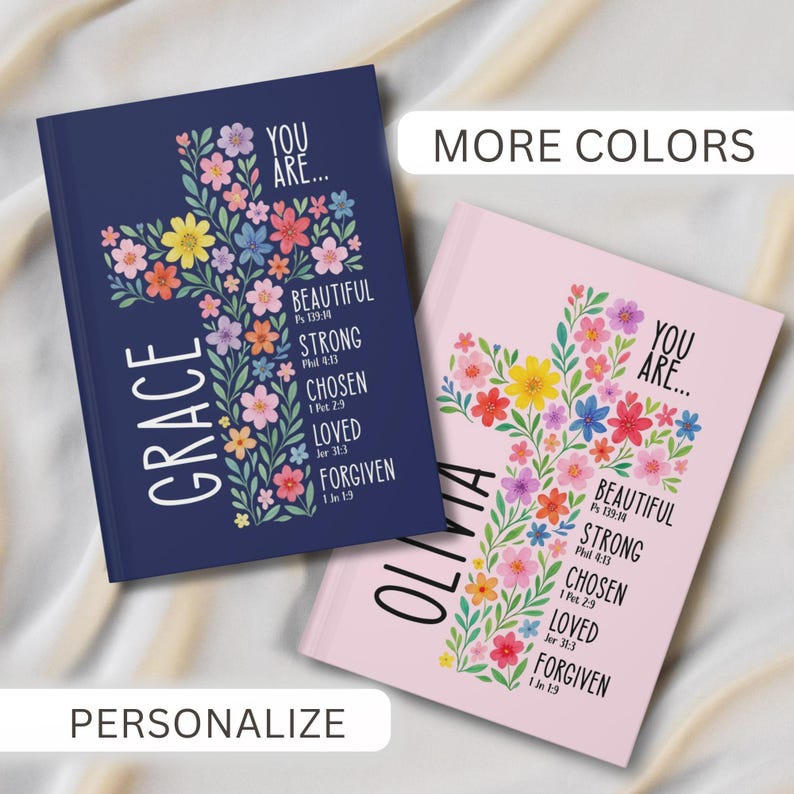 May include: Two journals with floral cross designs. One is navy blue with "GRACE" and the words "YOU ARE... BEAUTIFUL, STRONG, CHOSEN, LOVED, FORGIVEN." The other is pink with "OLIVIA" and similar text. The image also includes the words "MORE COLORS" and "PERSONALIZE."