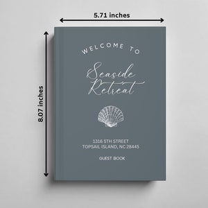May include: A grey guest book with the text "Welcome to Seaside Retreat" in white script font. A white seashell illustration is below the text. The address "1316 5th Street Topsail Island, NC 28445" and the text "Guest Book" are also in white. The book measures 20.5 cm by 14.5 cm.