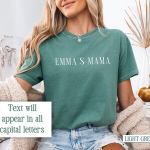 May include: A light green t-shirt with the text "EMMA'S MAMA" printed in white on the front. The text will appear in all capital letters.