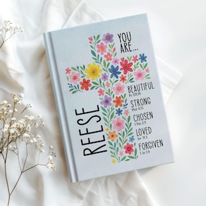 Personalized Christian journal for women and girls with a floral cross design on the cover. The front features “You Are” affirmations with Bible verses and a custom name option. Available in 8 colors, this faith-based notebook can be used for prayer journaling, Bible study notes, gratitude, reflections, and daily writing. Optional customization available for spine and back cover text. Feminine, inspirational gift idea for teens, women, church, or special occasions.