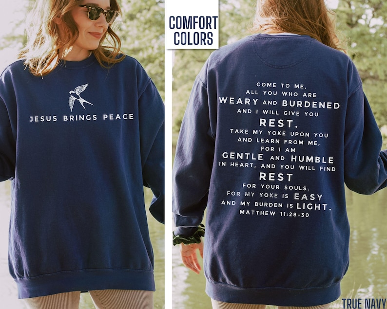 May include: Navy blue sweatshirt with a white bird graphic and the text "Jesus Brings Peace" on the front. The back of the sweatshirt has a white text quote from Matthew 11:28-30, "Come to me, all you who are weary and burdened and I will give you rest. Take my yoke upon you and learn from me, for I am gentle and humble in heart, and you will find rest for your souls. For my yoke is easy and my burden is light."