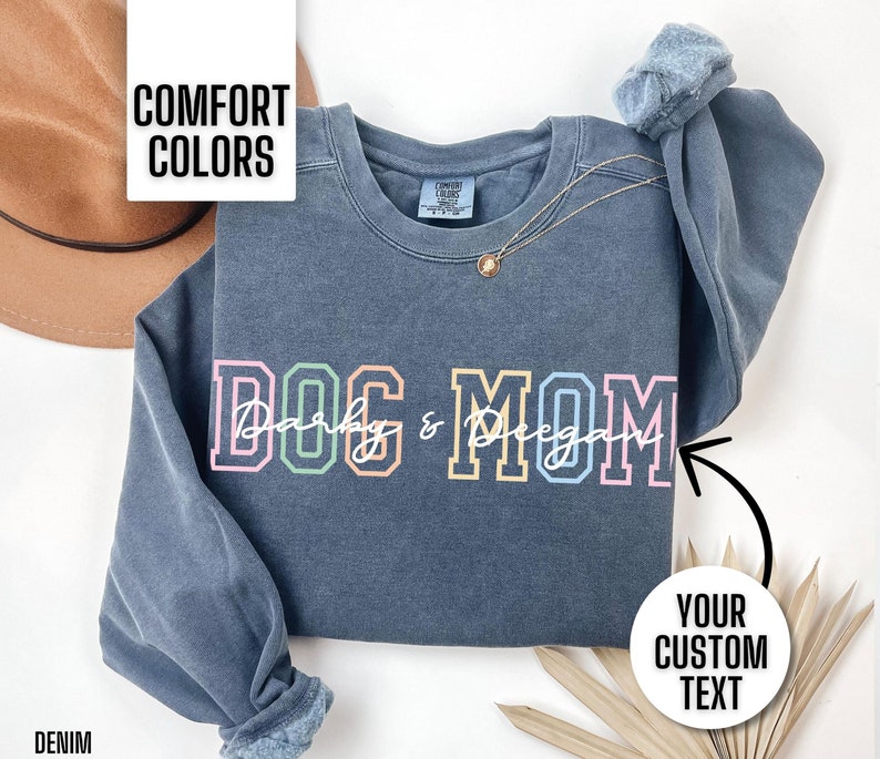 This personalized dog mom sweatshirt is so cute and comfortable. It says dog mom in a colorful text. You customize the overlay cursive font to say what you want. You can put your dog's names, dog breed, or nothing at all.