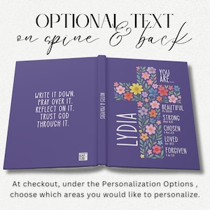 May include: Open purple journal with the text "WRITE IT DOWN. PRAY OVER IT. REFLECT ON IT. TRUST GOD THROUGH IT." on the left page. The right page features a floral cross design with the name "LYDIA" and the words "YOU ARE... BEAUTIFUL, STRONG, CHOSEN, LOVED, FORGIVEN."