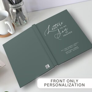Pu&ograve; includere: Un diario aperto, color verde acqua, con il titolo "Letters to my Son in Heaven" in elegante corsivo. Il diario include testo personalizzato con nome e date. Le parole "Front Only Personalization" sono in basso.