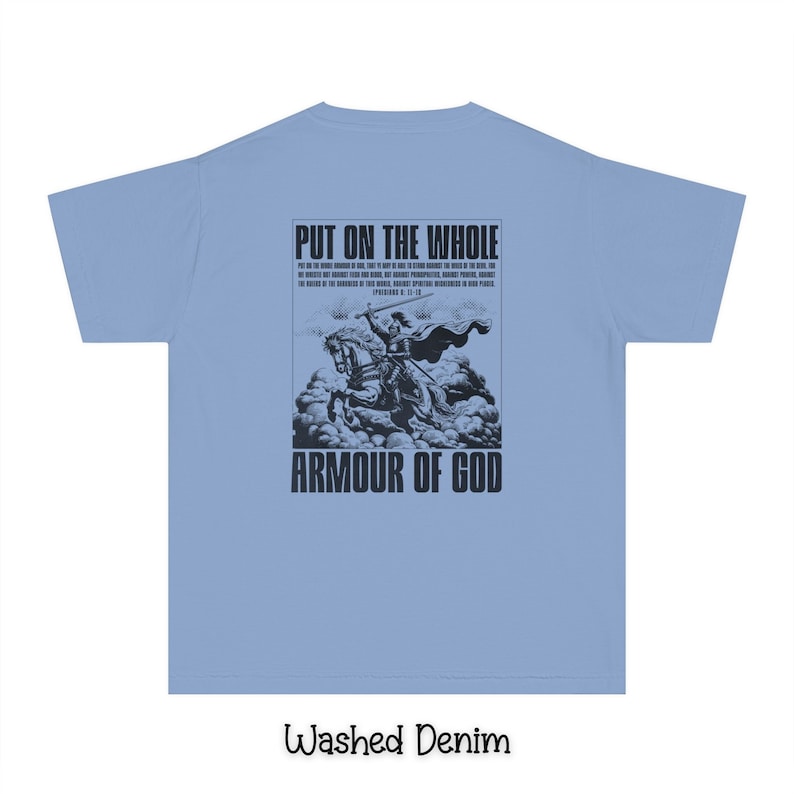 May include: A light blue t-shirt with a black graphic print of a knight on a horse. The graphic includes the text "Put on the whole armour of God" and a bible verse. The shirt is made of a washed denim fabric.