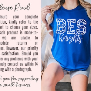 May include: Royal blue t-shirt with the text "BES Knights" in white, featuring a leopard print pattern within the letters. The shirt is made of a soft material. The text "TRUE ROYAL" is in the bottom right corner.