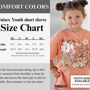Puede incluir: Camiseta de manga corta para j&oacute;venes de color terracota con dise&ntilde;o de calabaza y lazo. La tabla de tallas muestra las medidas en cm: XS (ancho 34.3, largo 47.6), S (ancho 36.8, largo 52.1), M (ancho 41.9, largo 54.6), L (ancho 44.5, largo 57.8), XL (ancho 49.5, largo 66.0).