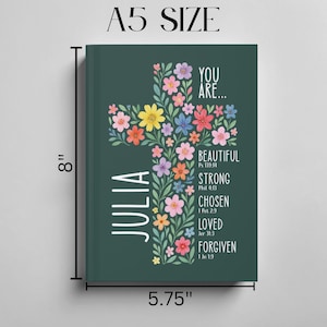 May include: A5 size journal with a dark green cover. The cover features a floral cross design with colorful flowers and the name "Julia" in white. Text includes "You Are... Beautiful, Strong, Chosen, Loved, Forgiven." The journal measures 8 inches tall and 5.75 inches wide.