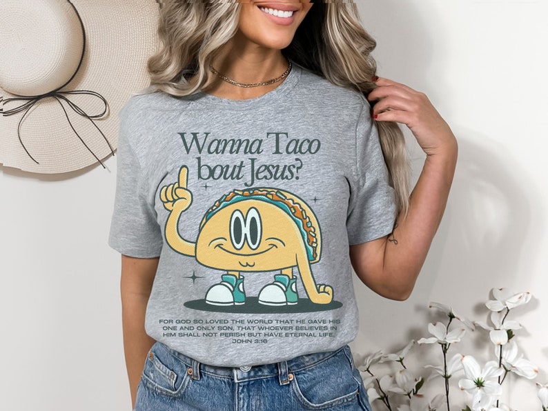 May include: Gray t-shirt with a cartoon taco wearing sneakers and pointing up. The text "Wanna Taco bout Jesus?" is above the taco. The text "FOR GOD SO LOVED THE WORLD THAT HE GAVE HIS ONE AND ONLY SON, THAT WHOEVER BELIEVES IN HIM SHALL NOT PERISH BUT HAVE ETERNAL LIFE. JOHN 3:16" is below the taco.