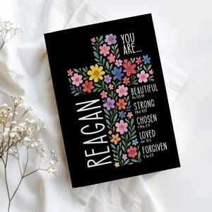 Personalized Christian journal for women and girls with a floral cross design on the cover. The front features “You Are” affirmations with Bible verses and a custom name option. Available in 8 colors, this faith-based notebook can be used for prayer journaling, Bible study notes, gratitude, reflections, and daily writing. Optional customization available for spine and back cover text. Feminine, inspirational gift idea for teens, women, church, or special occasions.
