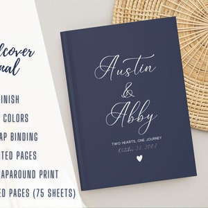 K&ouml;nnte beinhalten: Ein dunkelblaues Hardcover-Journal mit den Namen "Austin & Abby" und dem Text "Two Hearts, One Journey" in wei&szlig;er Schrift. Das Datum "October 23, 2003" ist ebenfalls in wei&szlig; gedruckt.