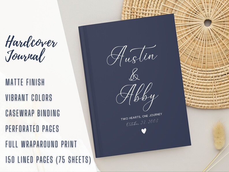 K&ouml;nnte beinhalten: Ein dunkelblaues Hardcover-Journal mit den Namen "Austin & Abby" und dem Text "Two Hearts, One Journey" in wei&szlig;er Schrift. Das Datum "October 23, 2003" ist ebenfalls in wei&szlig; gedruckt.
