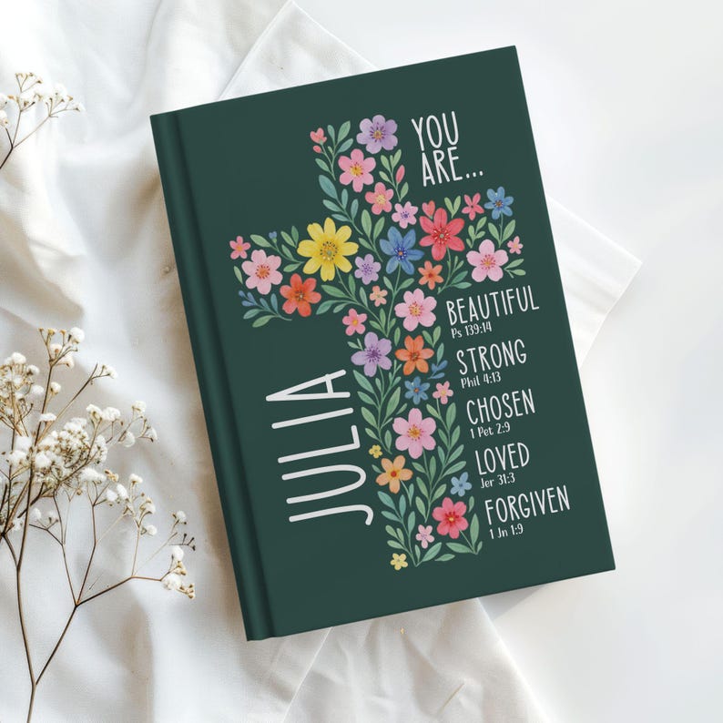 Personalized Christian journal for women and girls with a floral cross design on the cover. The front features “You Are” affirmations with Bible verses and a custom name option. Available in 8 colors, this faith-based notebook can be used for prayer journaling, Bible study notes, gratitude, reflections, and daily writing. Optional customization available for spine and back cover text. Feminine, inspirational gift idea for teens, women, church, or special occasions.