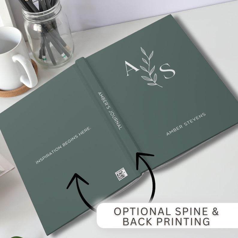 Może przedstawiać: Zielony dziennik z tekstem "Inspiration Begins Here." na okładce i "Amber's Journal" na grzbiecie. Tylna okładka zawiera inicjały "A S" z wzorem liści i imię "Amber Stevens".