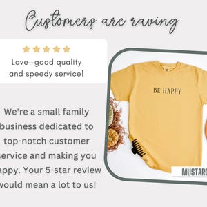 May include: A yellow t-shirt with the text "BE HAPPY" printed on the front. The shirt is laying flat on a white surface with a few decorative items around it. The text "MUSTARD" is printed in the bottom right corner of the image.