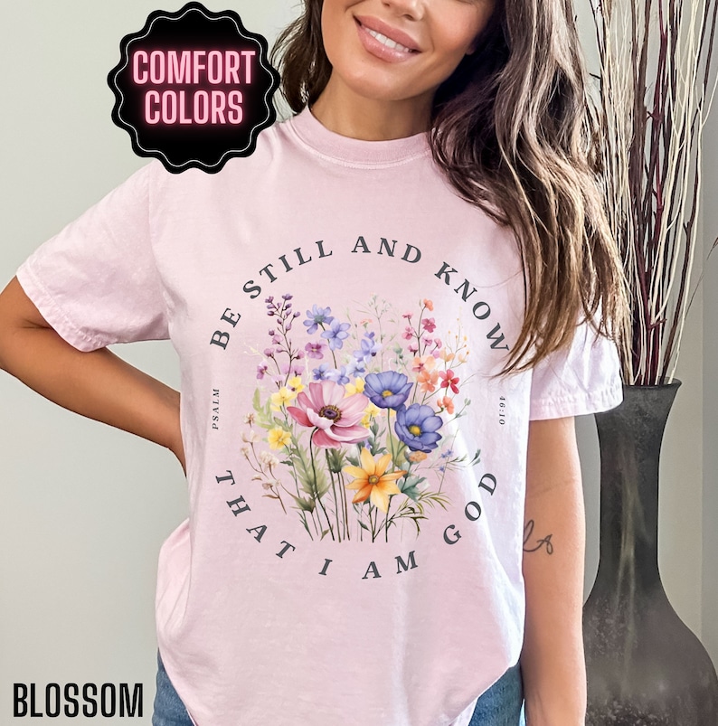 May include: A pink t-shirt with a floral design and the text "Be still and know that I am God" with the scripture reference "Psalm 46:10".