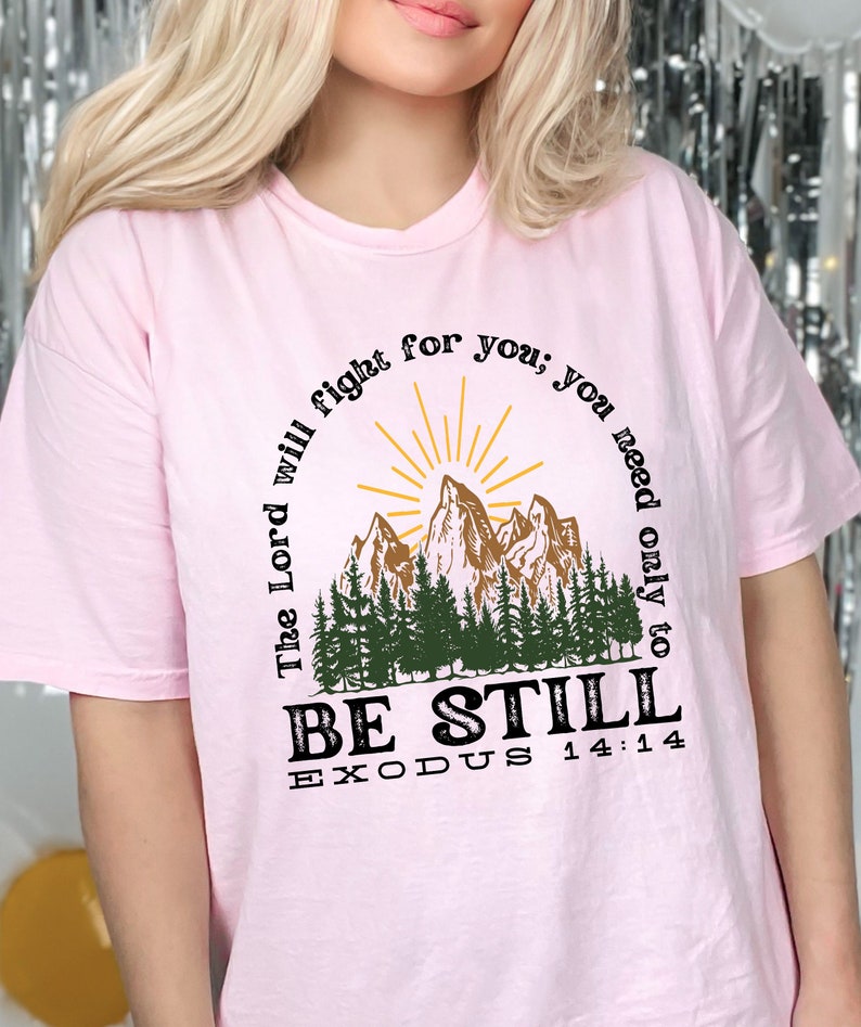 May include: Pink t-shirt with a mountain scene and the text "The Lord will fight for you; you need only to BE STILL EXODUS 14:14"