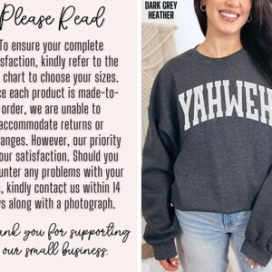 May include: Dark grey heather sweatshirt with the word "YAHWEH" in white arched lettering. The text "DARK GREY HEATHER" is at the top. The sweatshirt is worn by a person wearing blue jeans.