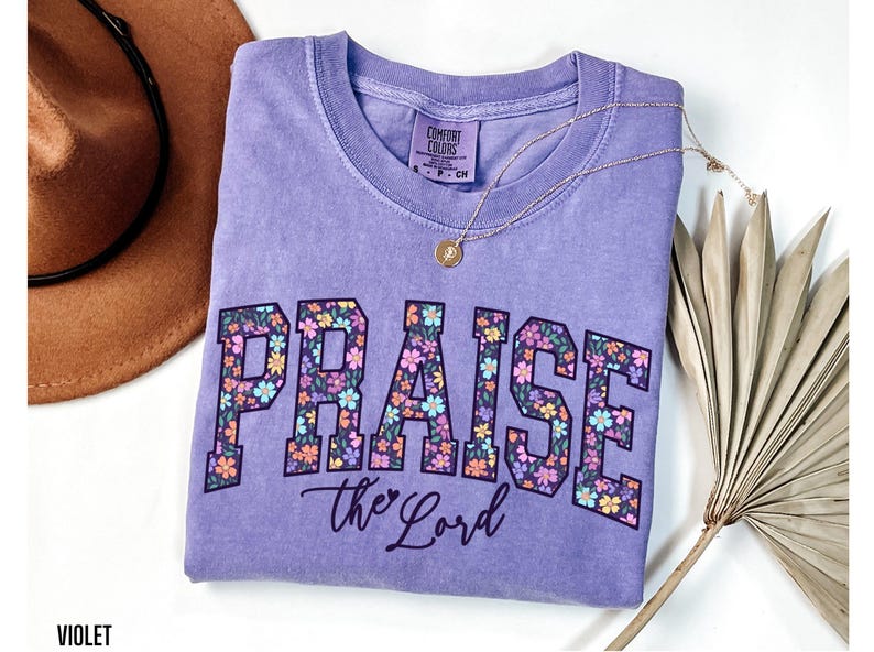 “Praise the Lord” Christian top with bold athletic-style font and a purple floral design. Printed on Comfort Colors t-shirts, sweatshirts, long sleeves, tank tops, and youth sizes. A joyful, uplifting faith-based shirt for Christian women who want to express worship and gratitude in style. Perfect for Bible study, church, or everyday spiritual encouragement. Feminine, colorful, and rooted in faith.