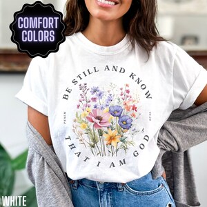 May include: White t-shirt with a floral design and the text "Be still and know that I am God" with the reference "Psalm 46:10".