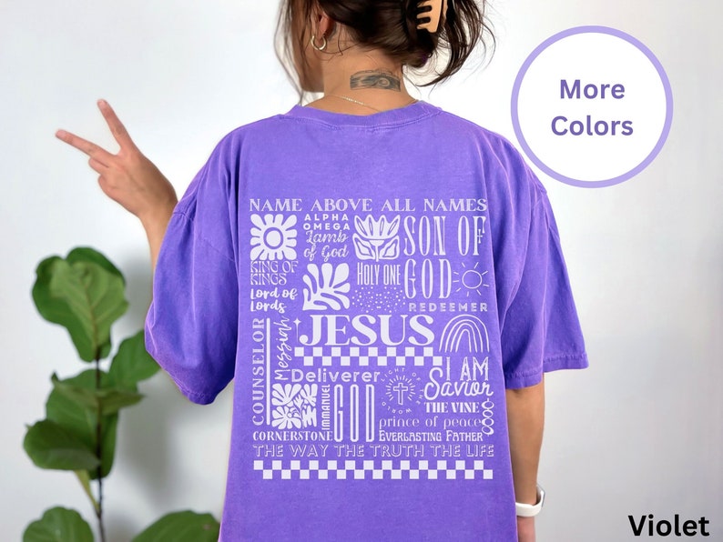 May include: Purple t-shirt with a white graphic design featuring the words "Name Above All Names", "Son of God", "Jesus", "I Am the Vine", and more. The graphic design also includes various religious symbols.