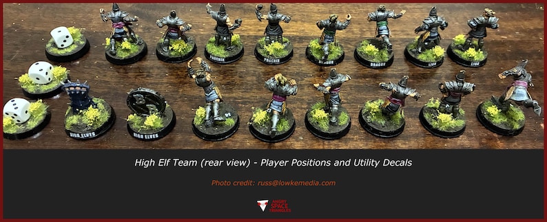 May include: A collection of painted miniature fantasy figures arranged in two rows on circular bases with green flocking, accompanied by three six-sided dice. The figures are viewed from the rear, displaying armour details and position markers.