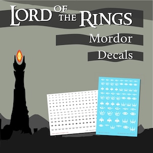Könnte beinhalten: Lord of the Rings Mordor Aufkleber. Das Bild zeigt die schwarze Silhouette des Turms von Barad-dûr mit dem Auge von Sauron. Zwei Aufkleberbögen sind abgebildet, einer weiß und einer blau, mit verschiedenen Augendesigns.