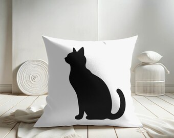May include: White pillow with a black silhouette of a cat sitting on it.