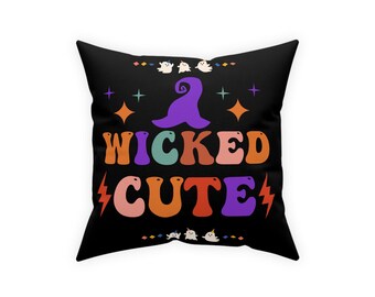 May include: A black throw pillow with a colorful graphic design. The design features a witch's hat, the words "Wicked Cute", and a few ghosts.
