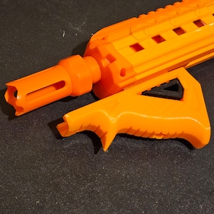Op de afbeelding: Fel oranje speelgoedpistool met een getextureerde behuizing en een handvat. Het pistool heeft een loop met een sleuf aan het uiteinde en een handvat. Het speelgoedpistool is gemaakt van plastic en is ontworpen voor kinderspel.