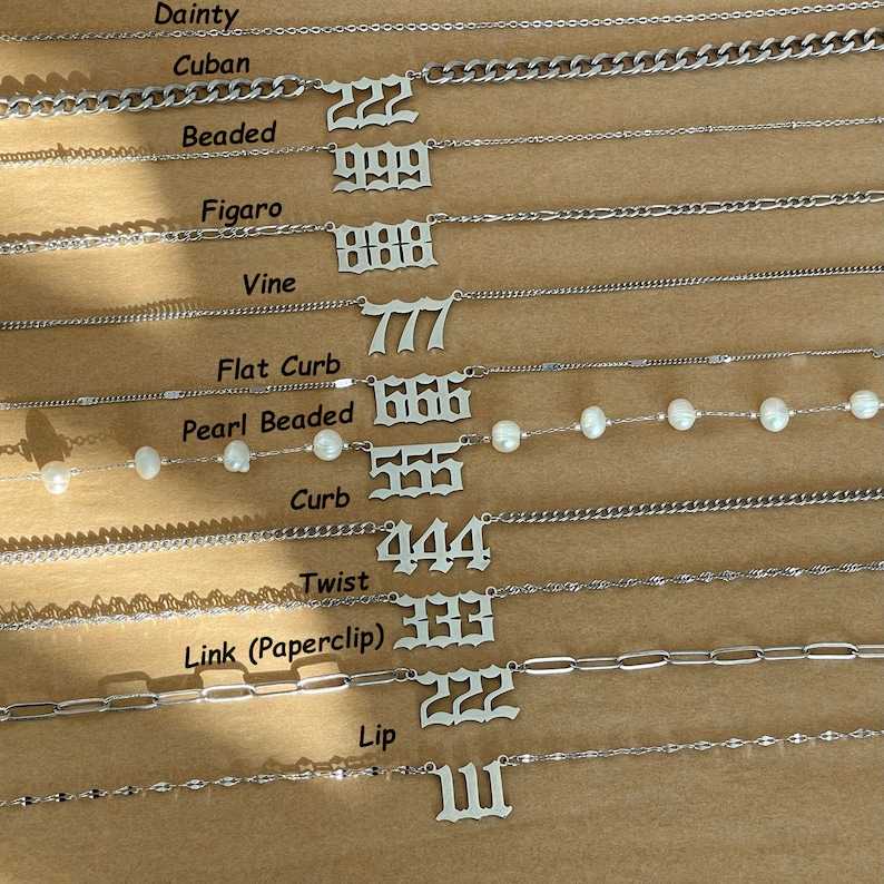 以下が含まれることがあります： さまざまなスタイルとリンクを持つ10本の異なるシルバーチェーンのクローズアップ。各チェーンには、111から999までの番号のペンダントが付いています。チェーンは垂直に配置されており、最大の番号が上、最小の番号が下にあります。
