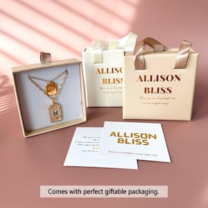 以下が含まれることがあります： 緑と白のアクセントがついた、正方形と長方形の2つのペンダントが付いたゴールドネックレス。ネックレスは、白いリボンと白いカードが入ったベージュの箱に入っています。カードには、金色の文字で「Allison Bliss」と書かれており、「あなたはあらゆる面でとても美しいです！」と書かれています。