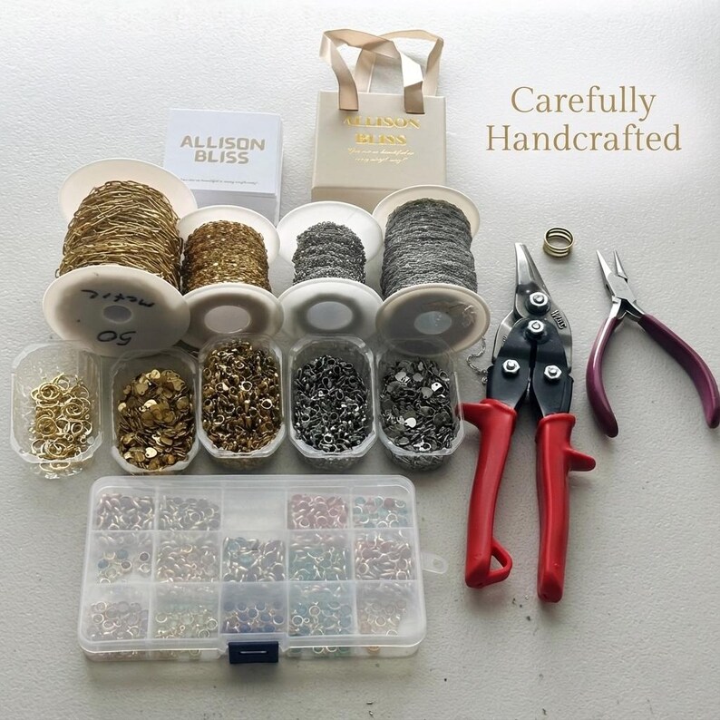 May include: A jewelry making kit featuring four spools of gold and silver chains, five small containers of metal jump rings, a multi-compartment plastic organizer box filled with colorful rings, metal snips with red handles, and pliers.