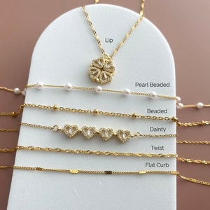 K&ouml;nnte beinhalten: Eine Kollektion goldfarbener Halsketten und Armb&auml;nder mit verschiedenen Kettenstilen, die als Lip, Pearl Beaded, Beaded, Dainty, Twist und Flat Curb beschriftet sind. Der Lip-Stil enth&auml;lt einen kleeblattf&ouml;rmigen Anh&auml;nger, w&auml;hrend der Dainty-Stil vier herzf&ouml;rmige Anh&auml;nger mit klaren Steinen aufweist.