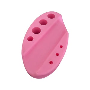 May include: Pink silicone tool with five holes for holding and drying nail art tools.