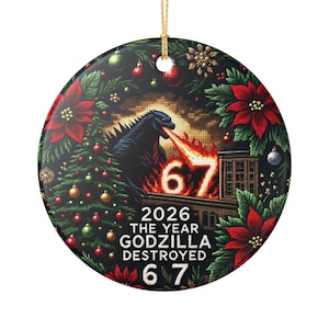 Op de afbeelding: Ronde kerstversiering met Godzilla die vuur spuwt op een gebouw. De versiering heeft een feestelijke rand van poinsettia's, dennennaalden en ballen. De tekst luidt "2026 The Year Godzilla Destroyed 67".