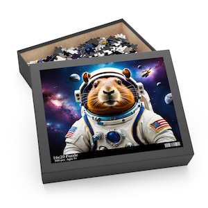 May include: A 16x20 inch puzzle box featuring a hamster astronaut in a space suit against a cosmic background. The box is open, revealing puzzle pieces. The puzzle image includes planets, stars, and a spaceship. The box text reads "16x20 Puzzle 500 pcs Ages 9+".