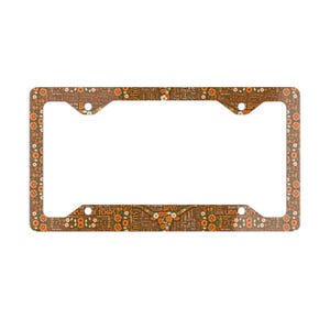 May include: Brown license plate frame with a floral and text design. The frame features the words "Texas", "Bevo", and "Horns" in a repeating pattern. The frame has a rectangular shape with rounded corners.