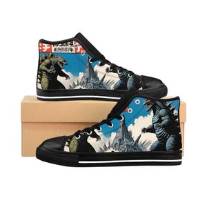 May include: Black high-top sneakers featuring a Godzilla graphic in a vintage Japanese style. The design includes Godzilla figures, buildings, and Japanese text against a blue sky background. The shoes have black soles and white stripes.