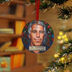 Puede incluir: Adorno navideño redondo con un retrato de un hombre con pelo gris. El adorno tiene una cinta roja para colgar y el texto "This Ornament Did Not Hang Itself". El fondo es un diseño de vidriera con acentos rojos y verdes.