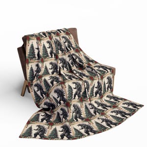 May include: A cream-coloured throw blanket with a repeating pattern of Godzilla standing in front of a Christmas tree. The trees are decorated with red baubles and green garland.