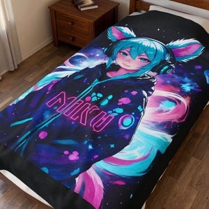 May include: A black blanket with a colourful anime-style character with blue hair and cat ears, wearing a black hoodie with the word "NIKU" in neon pink. The background is a galaxy design with pink and blue hues.