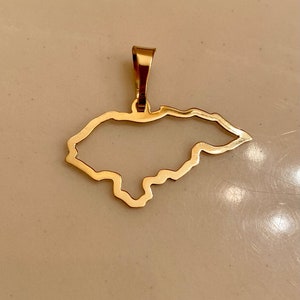 May include: A gold-colored pendant in the shape of the outline of Honduras.