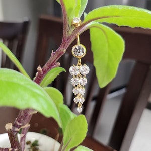 May include: Gold belly button ring with a dangling chain of clear rhinestones.